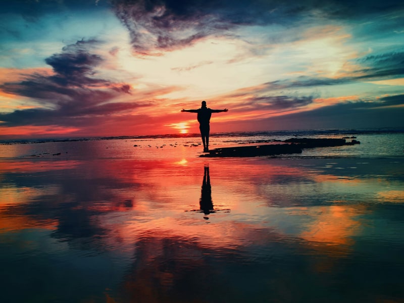 Person arms outstretched in glorious sunset